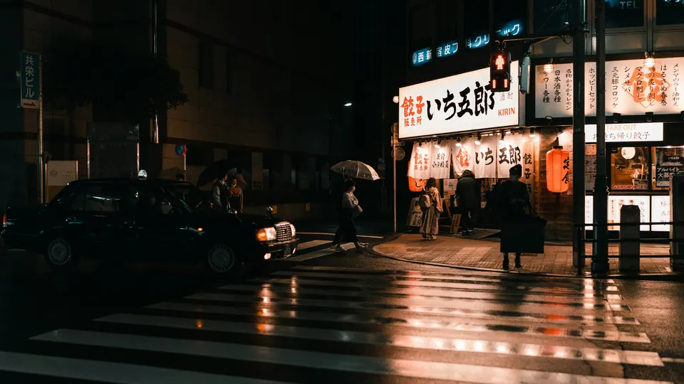Small group standing outside a lit shopfront on an otherwise dark street