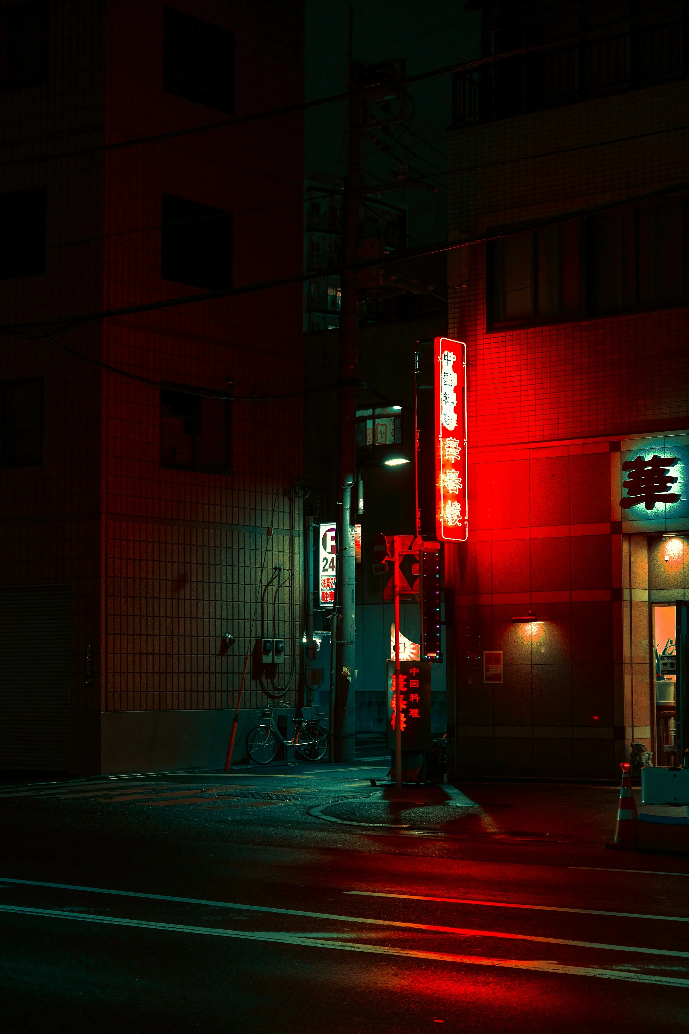 Empty street corner under a red-lit shop sign, the crossing bare of traffic