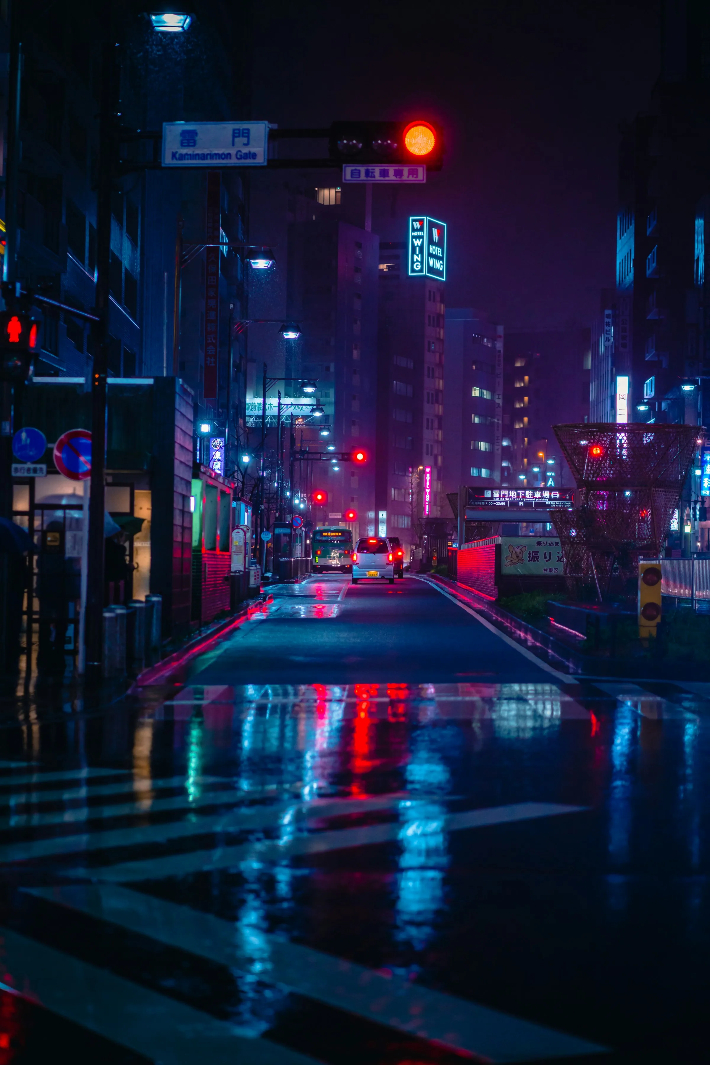 Wet road surface at night reflecting magenta and cyan signage in long vertical streaks